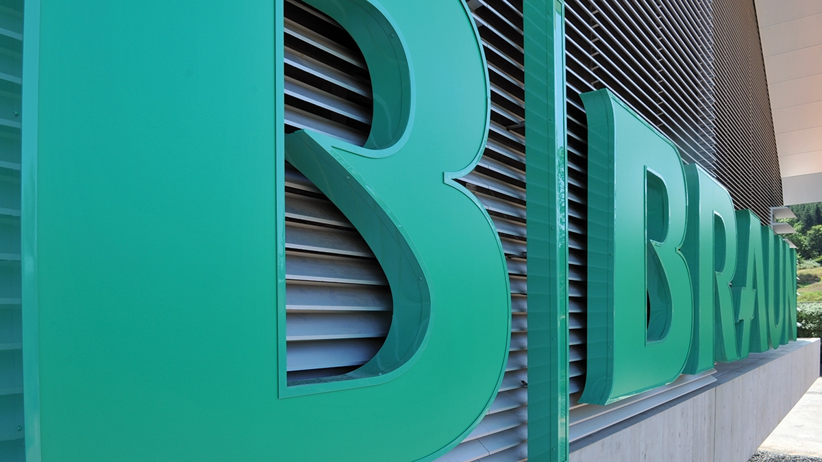 Detailní záběr trojrozměrného loga B. Braun na fasádě moderní budovy