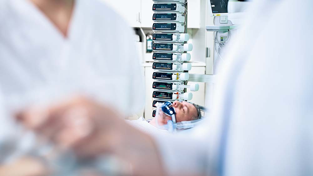 Pacient leží na jednotce intenzivní péče – v pozadí je mnoho infuzních pump B. Braun