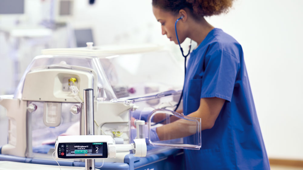 Sestra pečuje o pediatrického pacienta – chytré infuzní zařízení B. Braun v pozadí.